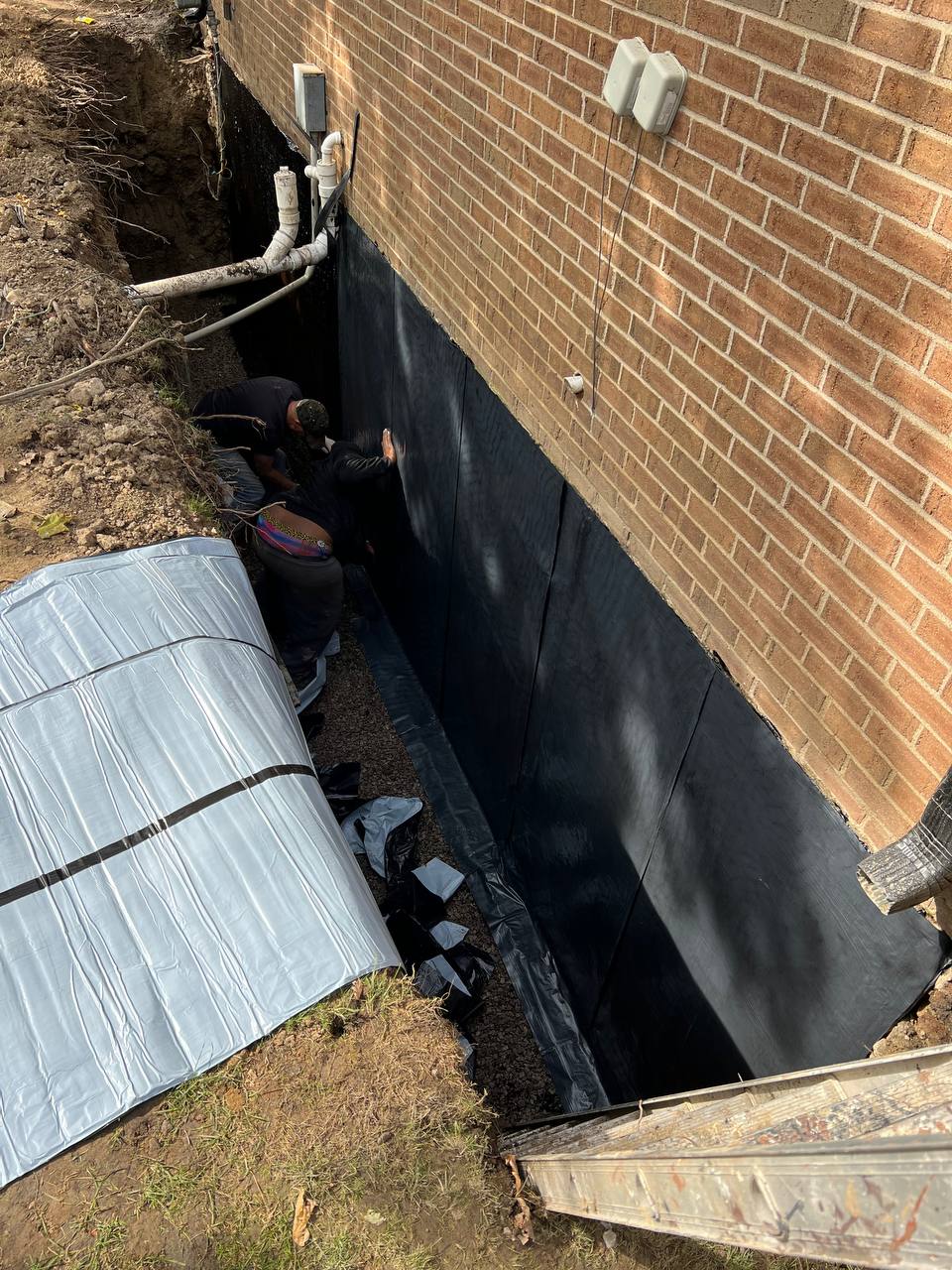 Black waterproof membrane applied to foundation exterior