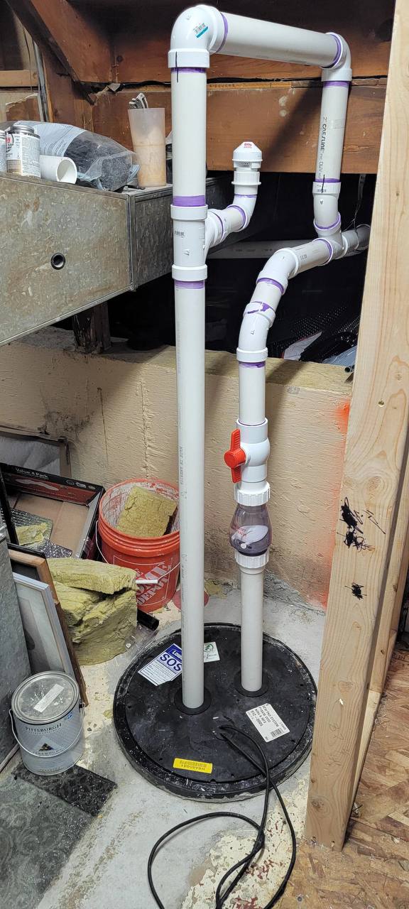 Finished sewage ejector installation with proper venting and code-compliant discharge piping